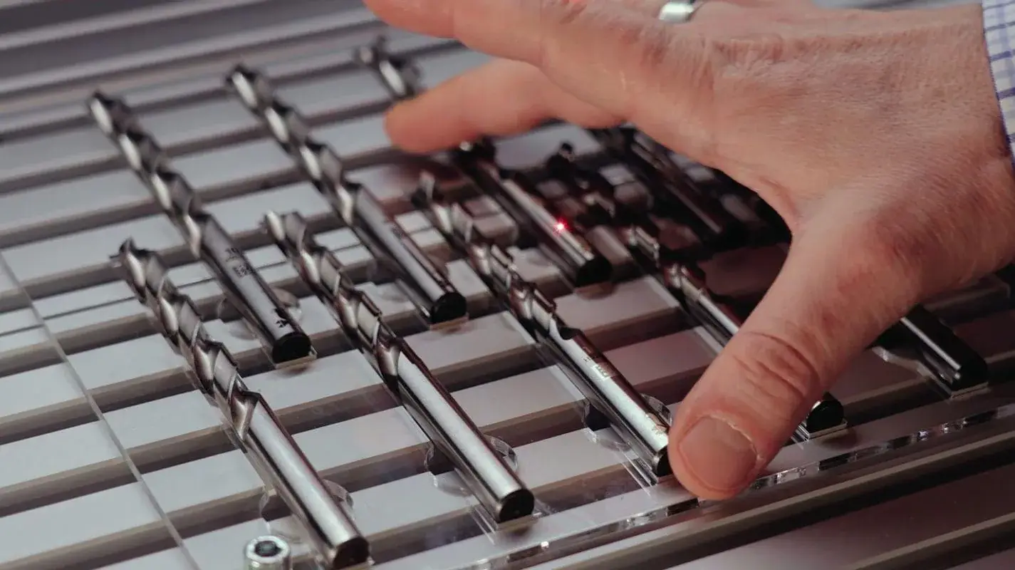 Main d’un opérateur au-dessus d’une série d’outils en acier alignés dans la machine de marquage